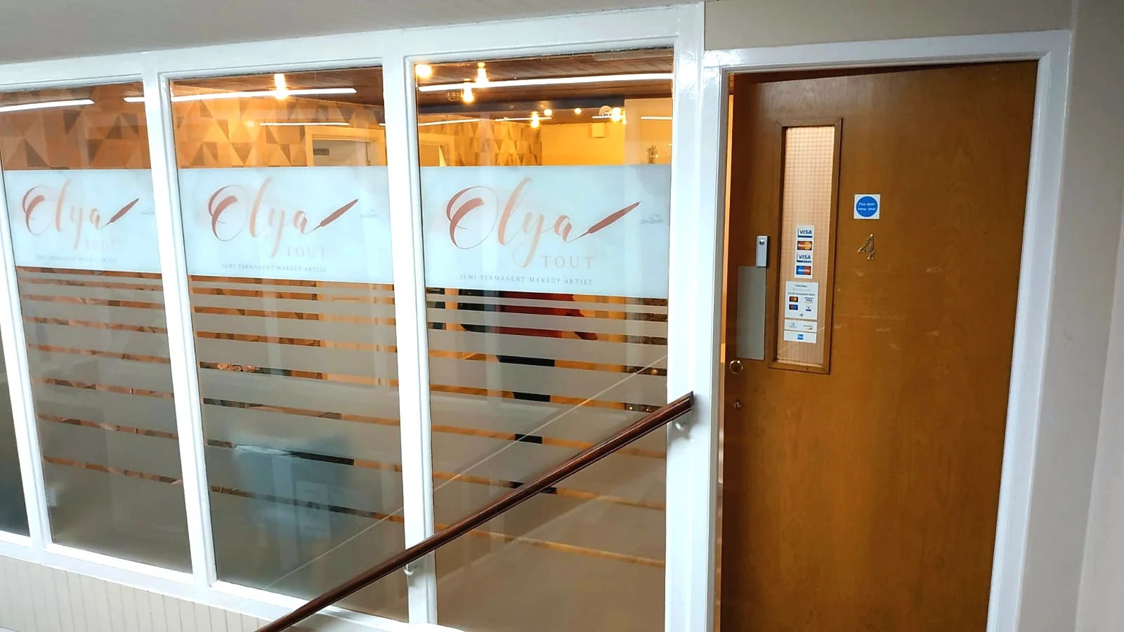 Unit 4 clinic door and Olya-branded windows on the first-floor landing.